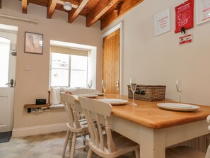 Un coin repas avec une table en bois, des chaises blanches et un panier en osier.