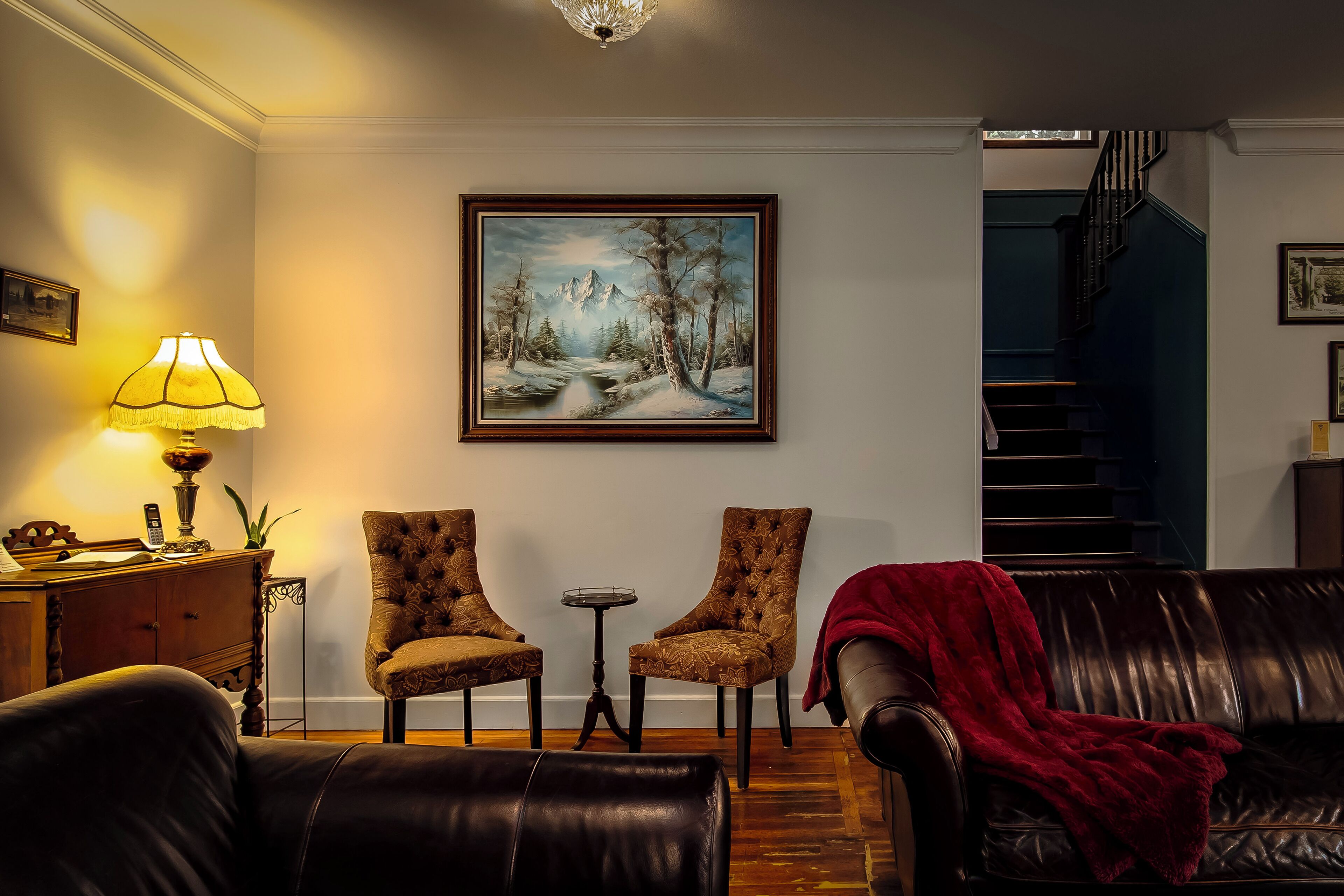A living room with a fireplace, two armchairs, a sofa, and a painting on the wall.