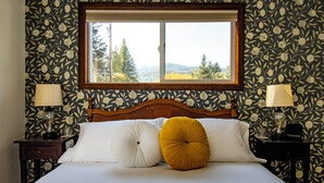 A bedroom with a wooden headboard, two bedside lamps, a window with a view of trees and mountains, and a bed with white and mustard-colored pillows. - #8 Silver Falls Trail Private Bath -Adults Only (Lewis County)