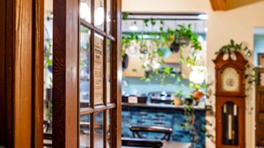 Una ventana de madera con un menú, una planta colgante, un reloj y una zona de bar al fondo.