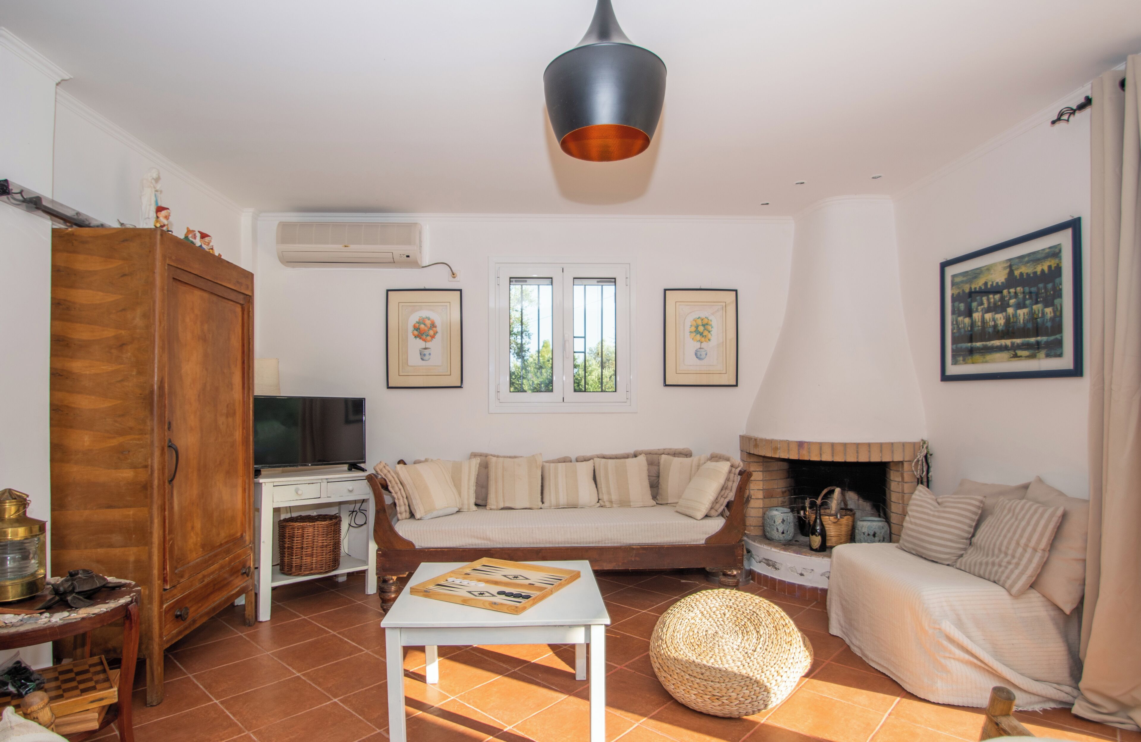 A living room with a sofa, a television, a fireplace, and a ceiling light.