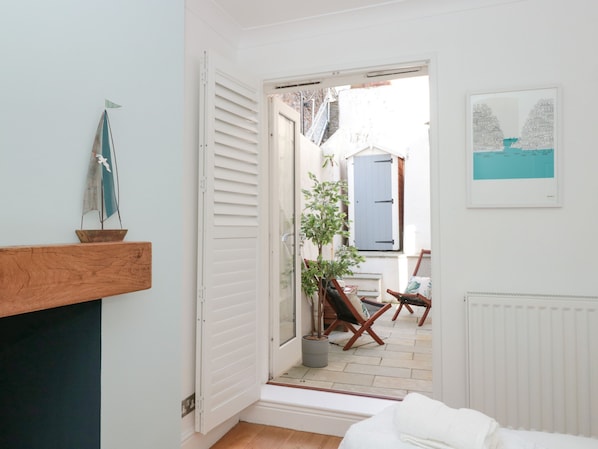 A narrow hallway leading to a balcony with a potted plant and two wooden chairs. - Avondale (Dartmouth)