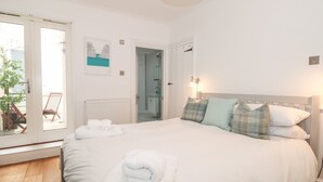 A bedroom with a large bed, a door leading to a bathroom, and a view of the outside.
