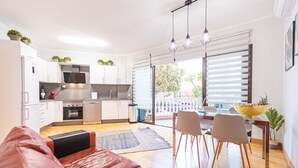 A modern kitchen with white cabinets, a built-in oven, and a dining area with a table and chairs. - Amazing Duplex with panoramic ocean views  (Costa Adeje)