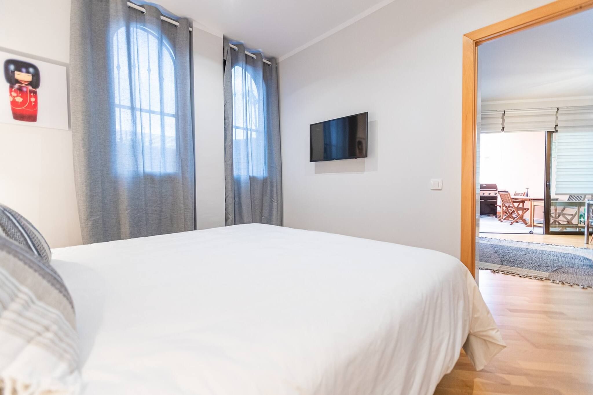 Une chambre avec un lit, un téléviseur à écran plat et une vue sur un patio extérieur.