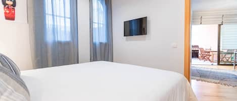 Ein Schlafzimmer mit einem Bett, einem Flachbildfernseher und Blick auf eine Terrasse.