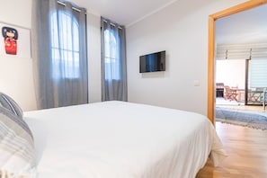 Ein Schlafzimmer mit einem Bett, einem Flachbildfernseher und Blick auf eine Terrasse.