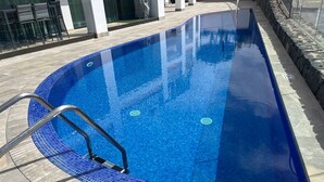 A swimming pool with a blue tiled edge, a metal ladder, and a stone border. - Amazing Duplex with panoramic ocean views  (Costa Adeje)