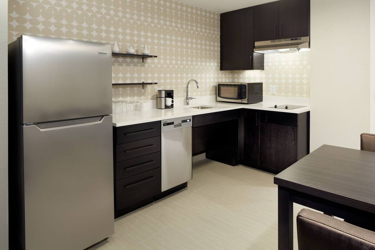 A modern kitchen with a refrigerator, microwave, sink, and dishwasher.