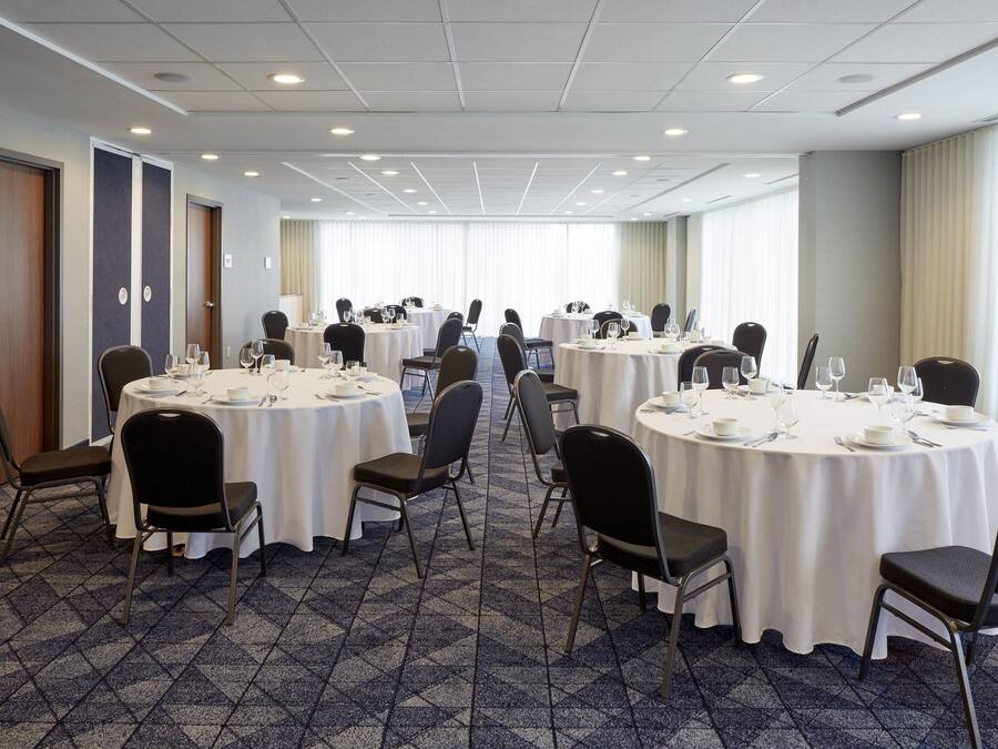 A conference room with multiple round tables, each set with chairs and dining essentials.