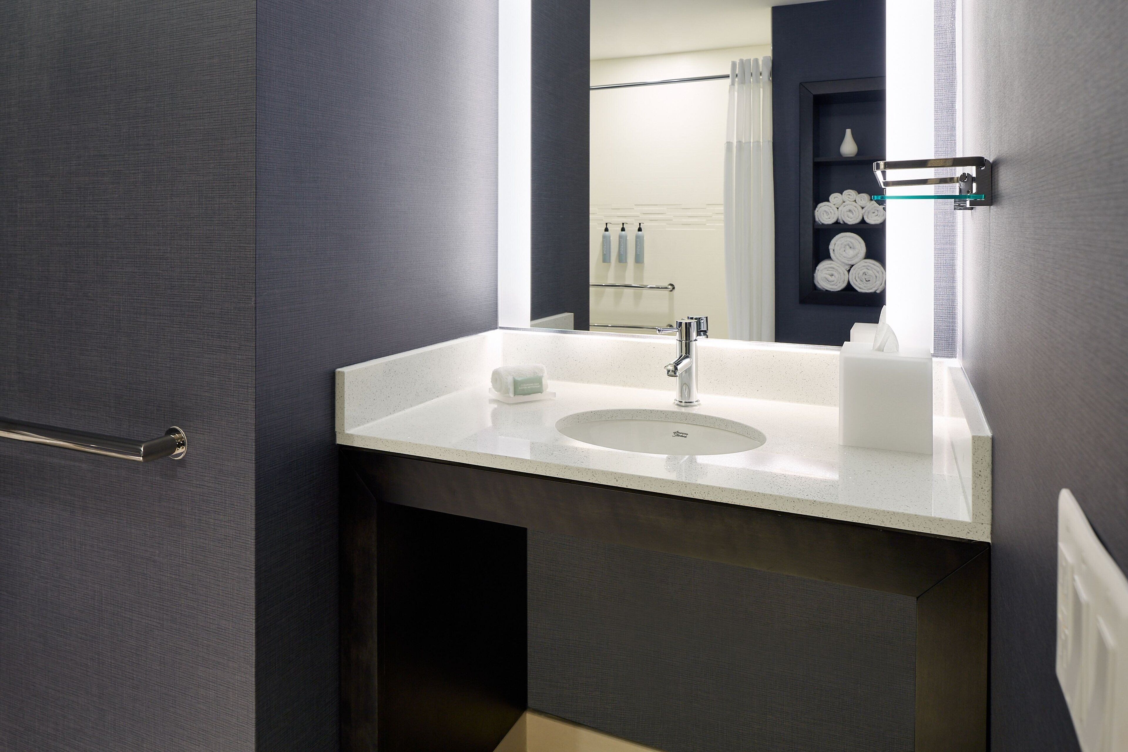 A modern bathroom with a white sink, a mirror, and a towel rack.