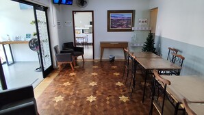 A conference room with a wooden floor, a large table, and chairs. There is a television on the wall and a framed picture. - Novo Hotel (Itajuba)