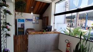 A reception area with a wooden ceiling, a counter, a refrigerator, and a potted plant. - Novo Hotel (Itajuba)