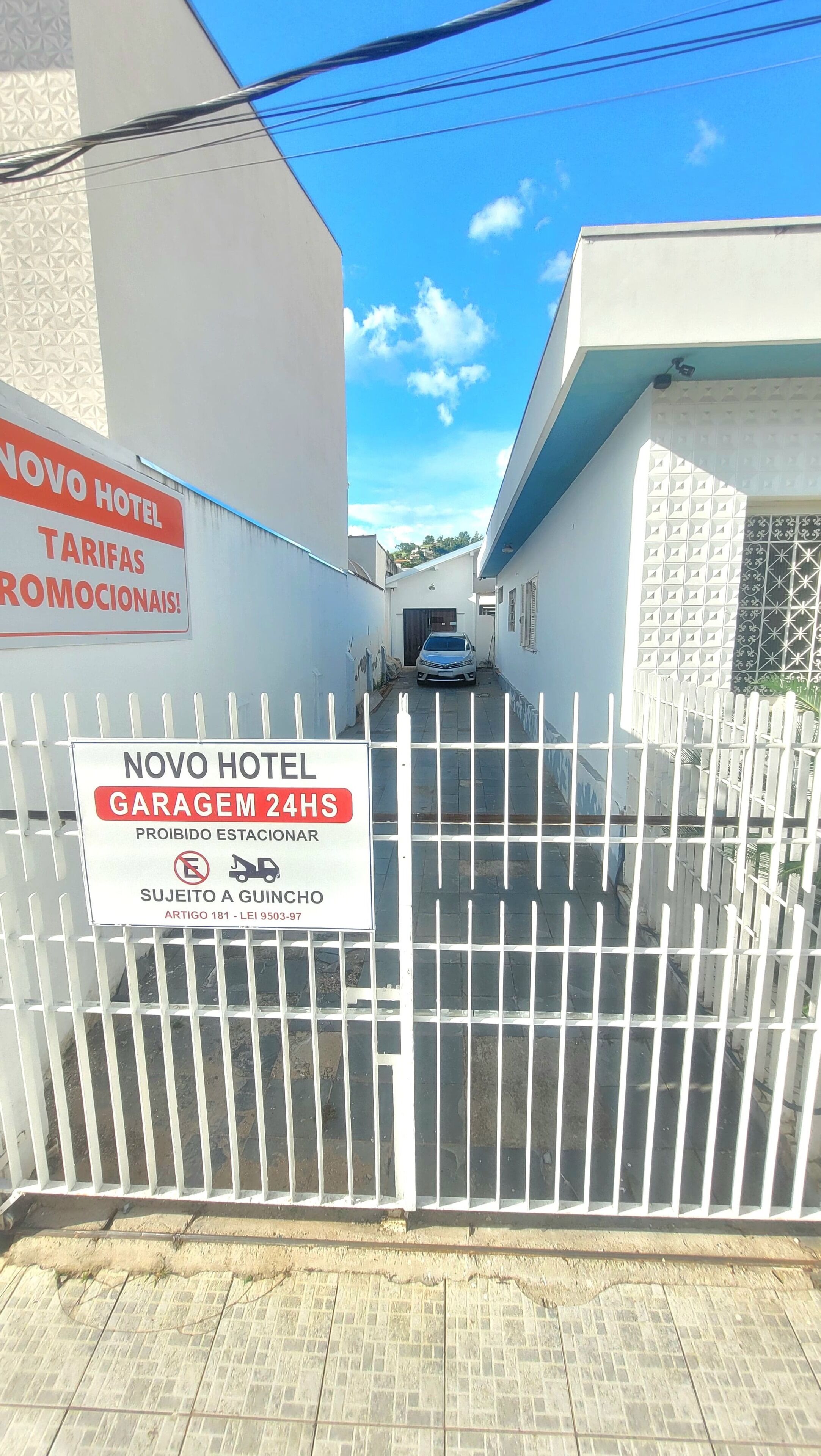 Una entrada cerrada al Hotel Novo, con un letrero que indica un garaje disponible las 24 horas y la prohibición de estacionamiento.