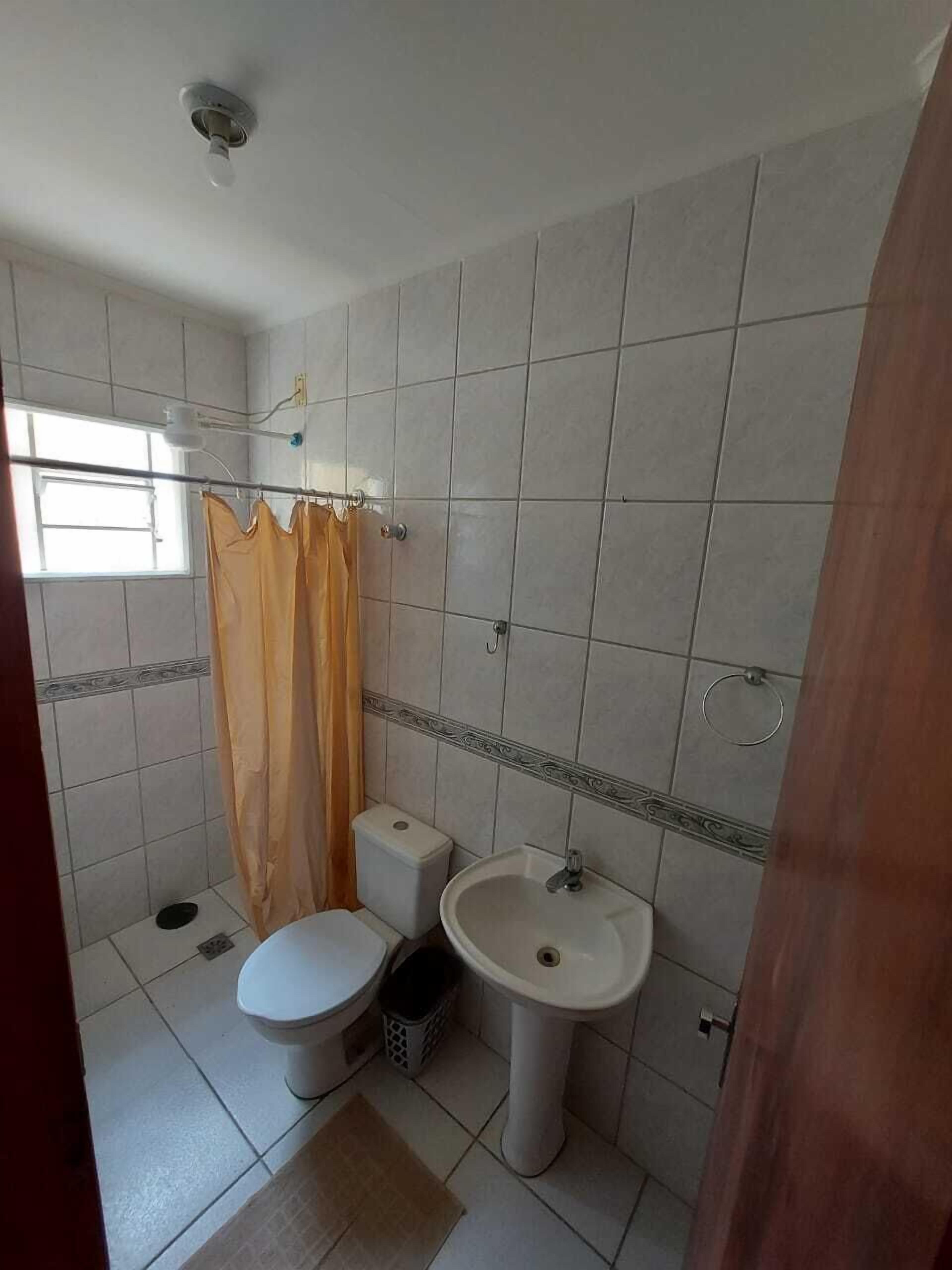 Une salle de bain avec des toilettes, un lavabo et un rideau de douche.