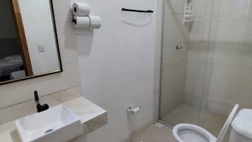 Une salle de bain équipée d’un lavabo, de toilettes, d’une douche et d’un miroir.