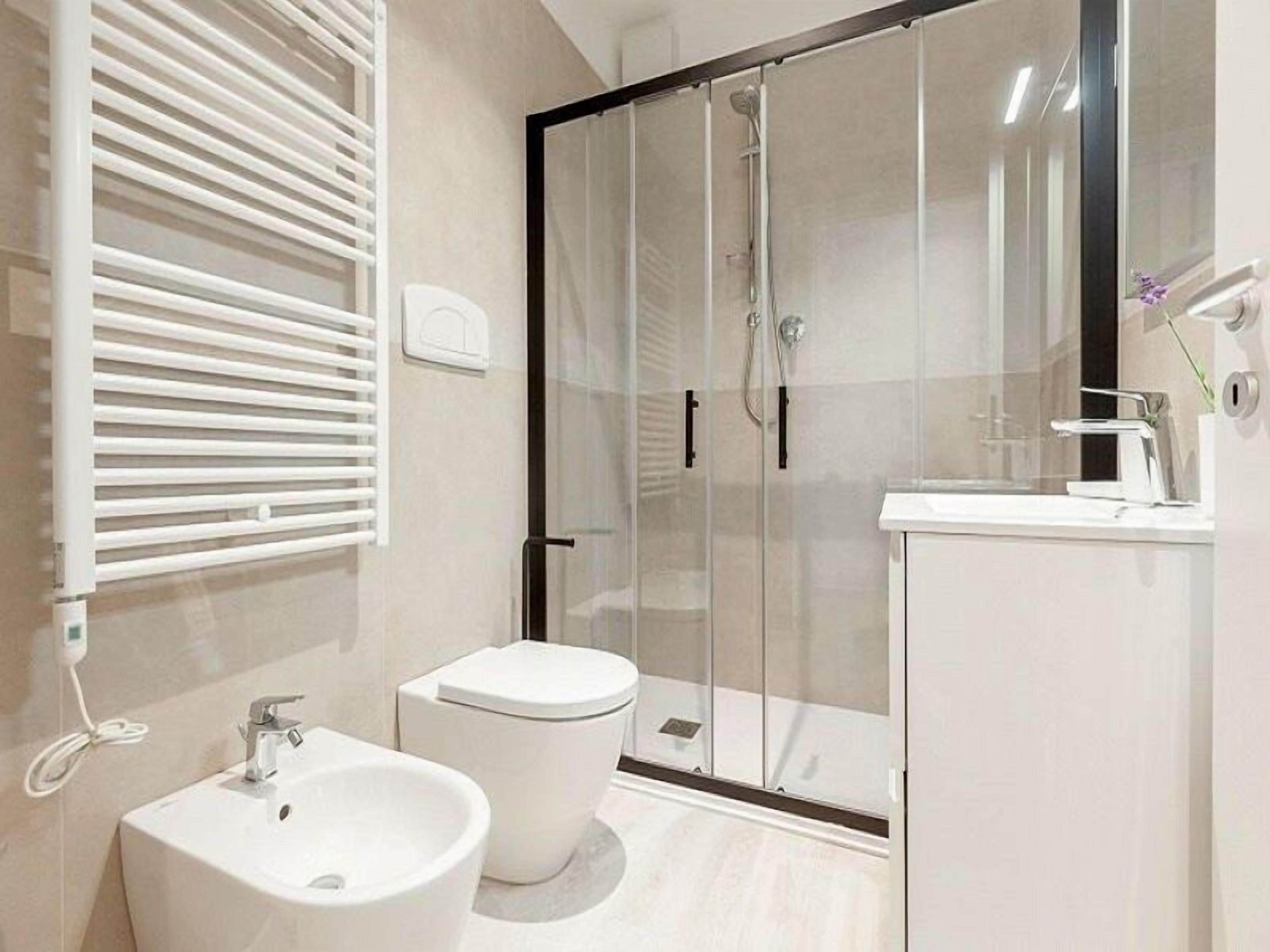 Ein modernes Badezimmer mit einer Duschkabine, einem weißen Waschbecken und einer Toilette.