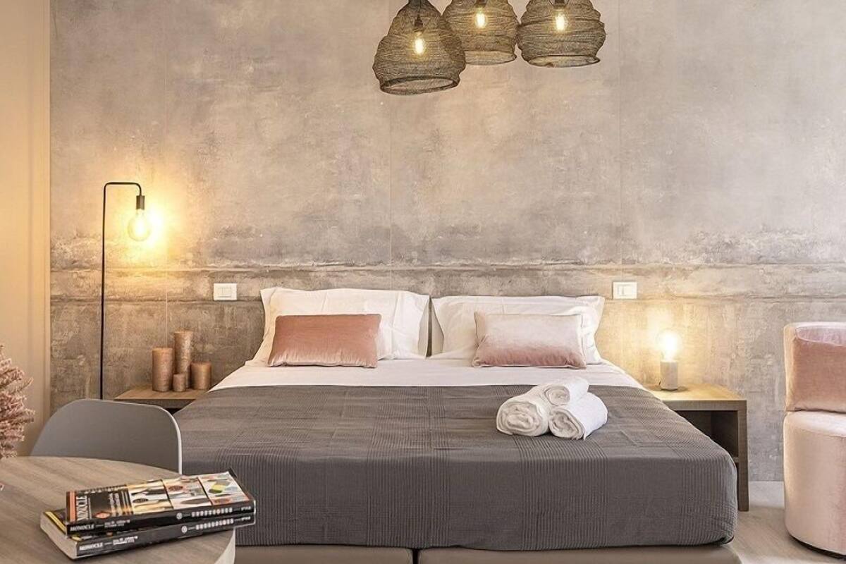 A modern bedroom with a large bed, two bedside lamps, and a wall-mounted light fixture.