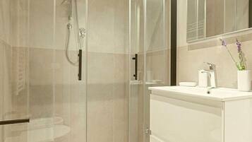 A modern bathroom with a glass-enclosed shower, a white sink, and a mirror above it.