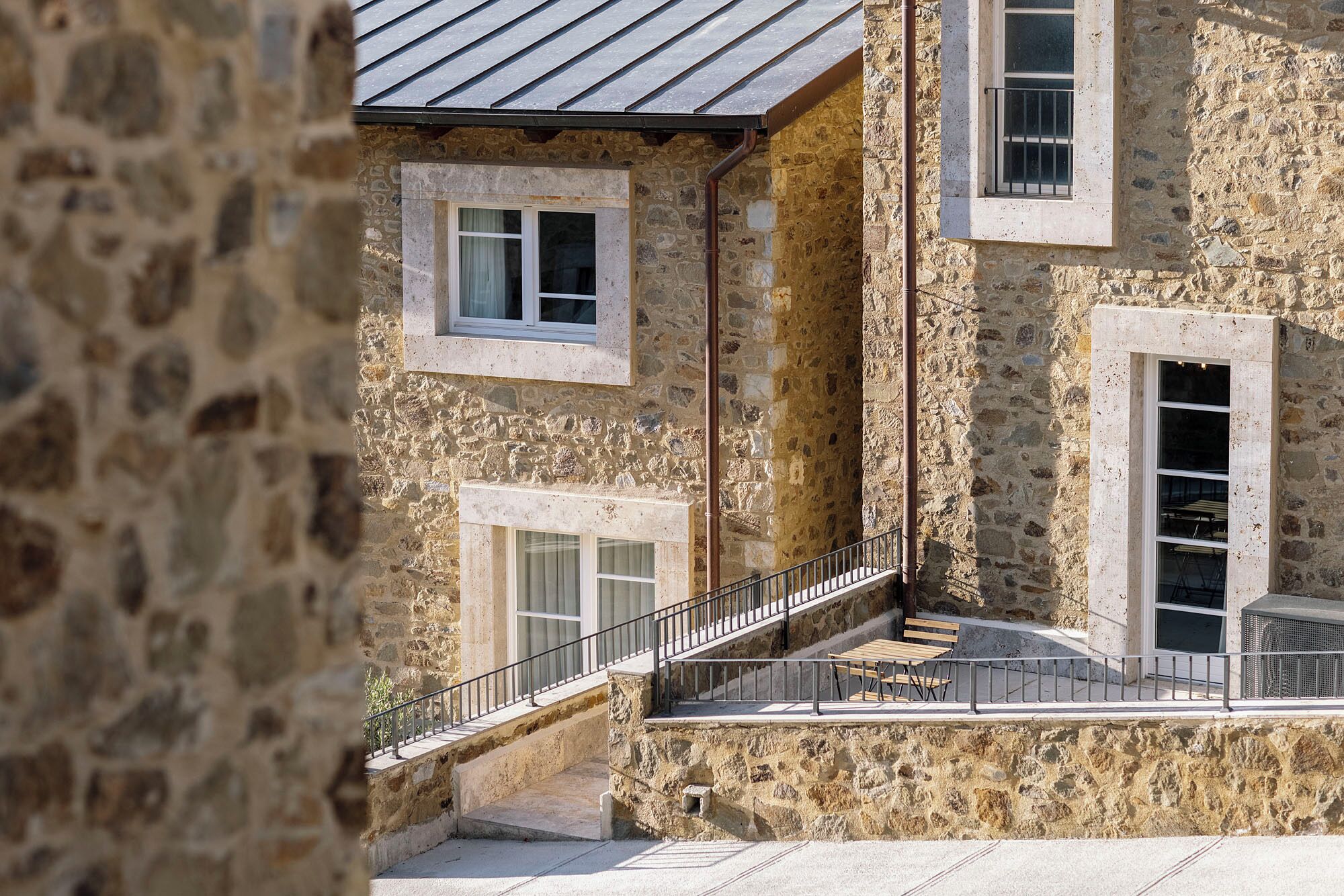 A stone building with multiple windows, a staircase, and a metal railing.