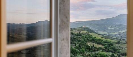 A view through a window of a landscape with rolling hills and a distant mountain range.