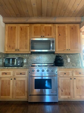 A kitchen with wooden cabinets, a microwave, a toaster, and a stainless steel oven.