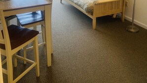 Ein Zimmer mit einem Holztisch, Stühlen, einer Couch, einer Lampe und einem Bild an der Wand.