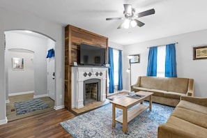 Un salon avec une cheminée, un canapé, une table basse et un ventilateur de plafond.