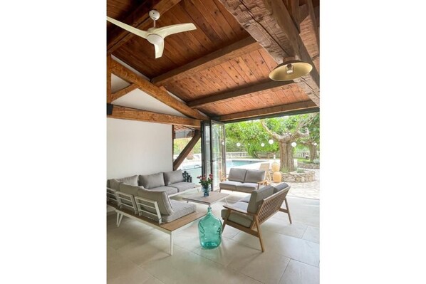 Un espace intérieur spacieux avec un plafond en bois, un canapé, un fauteuil et une table basse.