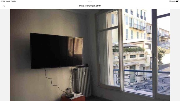 A room with a mounted television, a radiator, and a window with a view of buildings. - Carre d or, 50m Mer, Superbe Appart (Nice)