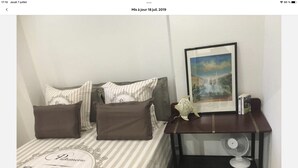 A neatly arranged bedroom with a bed, pillows, a bedside table with a fan, and a framed picture on the wall. - Carre d or, 50m Mer, Superbe Appart (Nice)