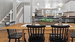 A dining area with a wooden table, black chairs, a central plant, and pendant lighting. - Heated Pool and Hot Tub -Casa Bonita An Irvie Home (Albuquerque)