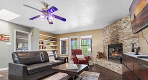A living room with a fireplace, a leather sofa, a coffee table, and a bookshelf.