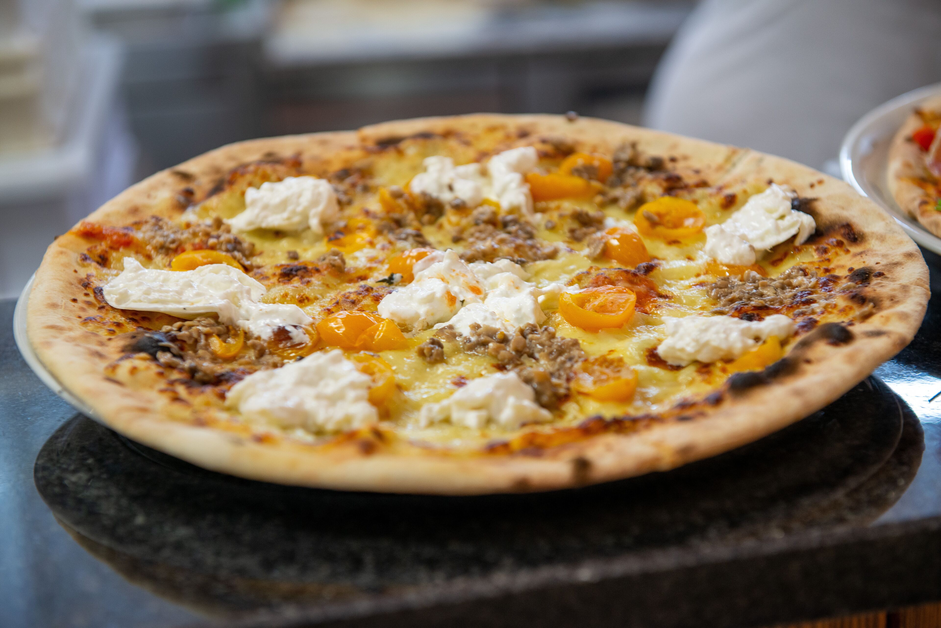 Una pizza con condimenti su una superficie nera.