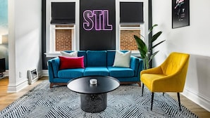 Un salon moderne avec un canapé bleu, un fauteuil jaune et une table basse noire.