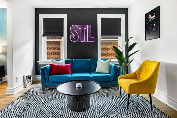 A modern living room with a blue sofa, a yellow armchair, and a black coffee table.
