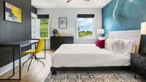 Une chambre moderne avec un lit, un bureau, une chaise, un ventilateur de plafond et une vue sur l’extérieur.
