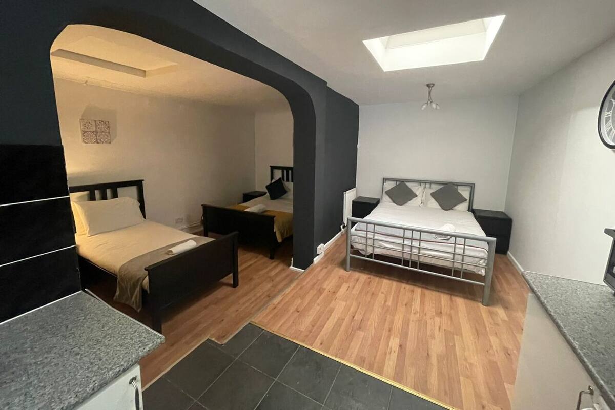 A compact bedroom with two beds, a skylight, a small desk, and a wardrobe.