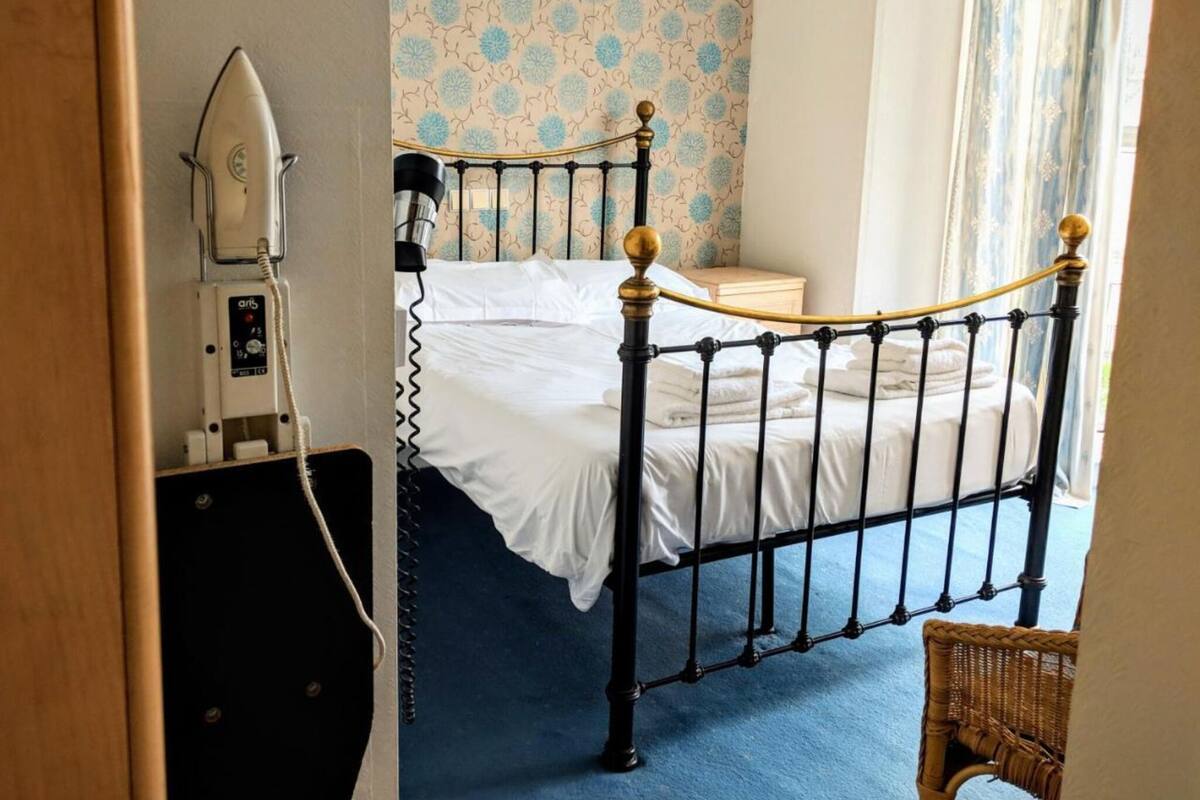 A single bed with a black metal frame and wooden headboard, a bedside table, and a lamp.