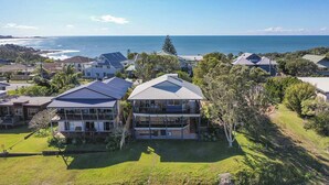 A residential area with houses, a large lawn, and a view of the ocean. - Baan Sabai - Oceanstays (Angourie)
