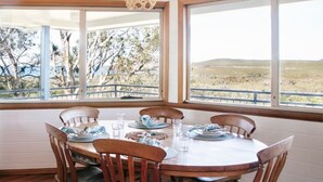 A dining area with a round table, wooden chairs, and large windows offering a view of a desert landscape.