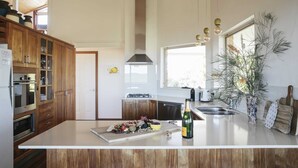 A modern kitchen with wooden cabinets, a large island, and a view of the outdoors.