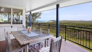 A wooden deck with a table and chairs, overlooking a scenic landscape.