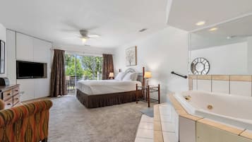 Habitación de hotel con cama, televisor, sofá, baño con bañera y balcón con cortinas.