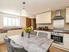 Una cocina moderna con una mesa de comedor, sillas, horno empotrado y campana extractora de acero inoxidable.