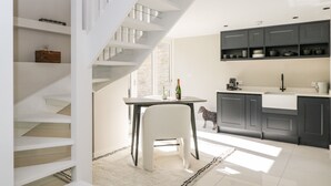 Eine moderne Küche mit Treppe, Esstisch und weißem Stuhl.