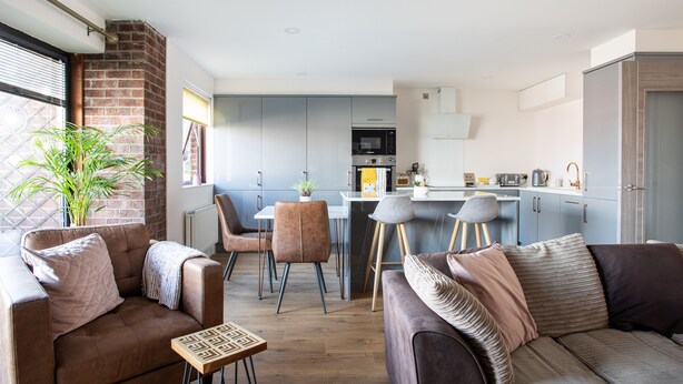 A modern living room with a sofa, a coffee table, and a dining area with chairs and a table.