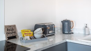 A kitchen counter with a toaster, a kettle, a coffee maker, a bag of chips, and a sign that reads "The Wifi Password is".