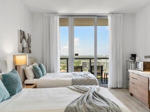 Two large beds with neutral-toned bedding and ample pillows. Enjoy city views from the large window.