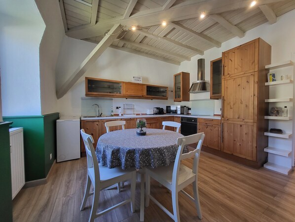 A cozy kitchen with wooden cabinets, a dining table with chairs, and a built-in oven. - Nid douillet 2ou4 p à St Pierre de Chartreuse (Saint-Pierre-de-Chartreuse)